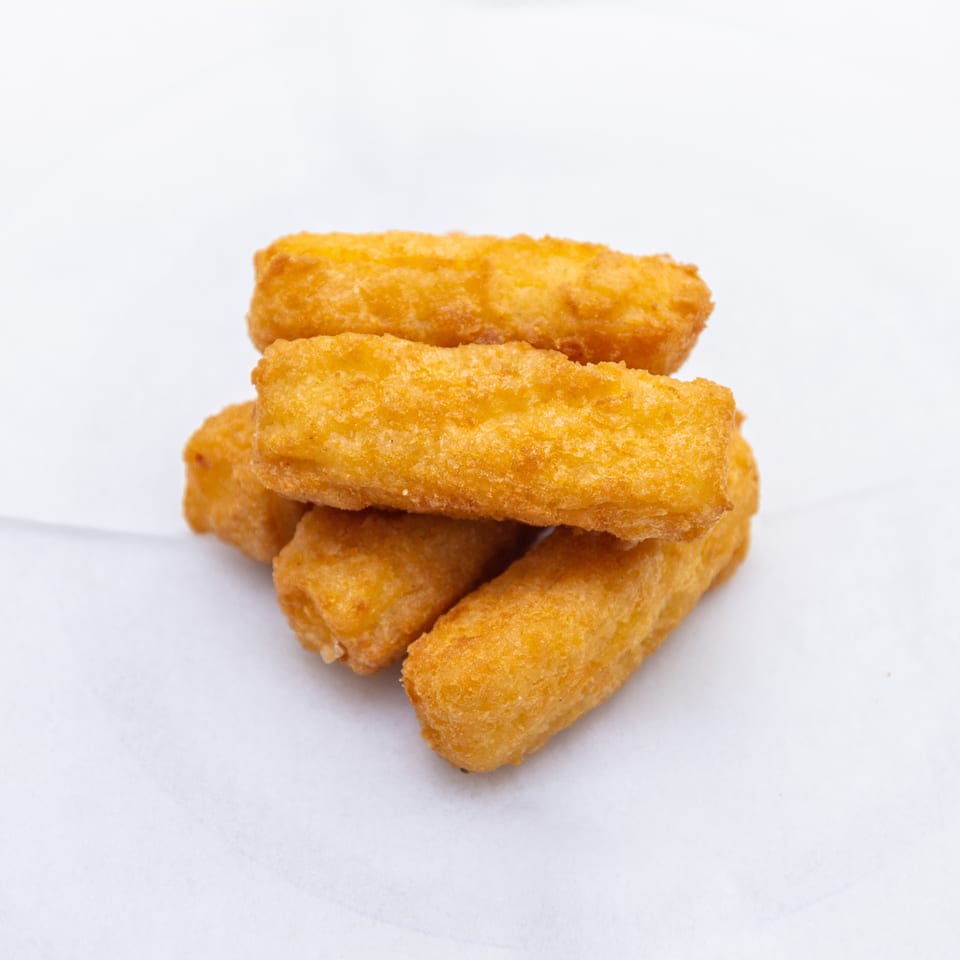 Stack of golden-brown breaded rectangular fried pieces arranged on white paper.